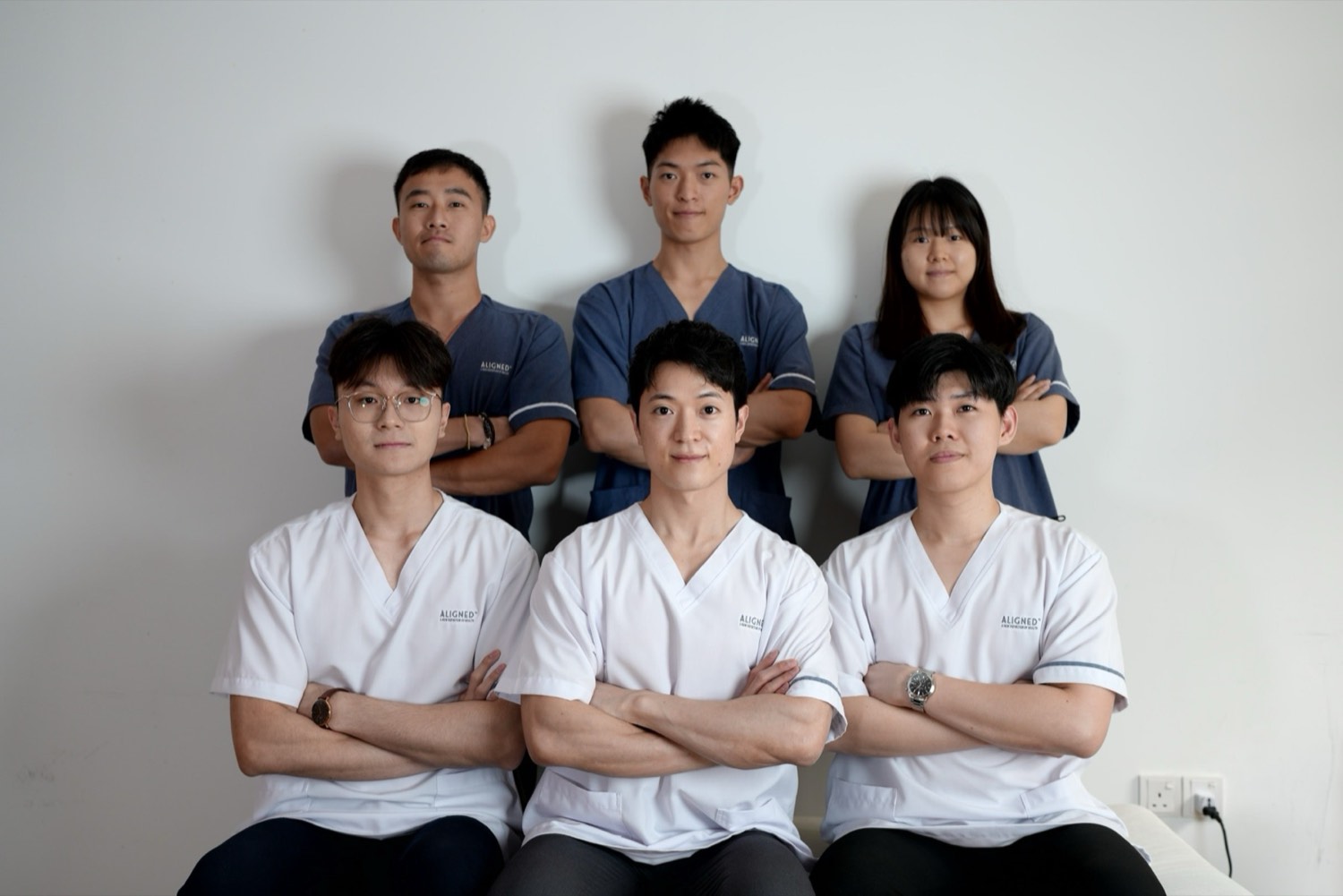 The Aligned clinical team in white and navy scrubs, arms folded, at the clinic